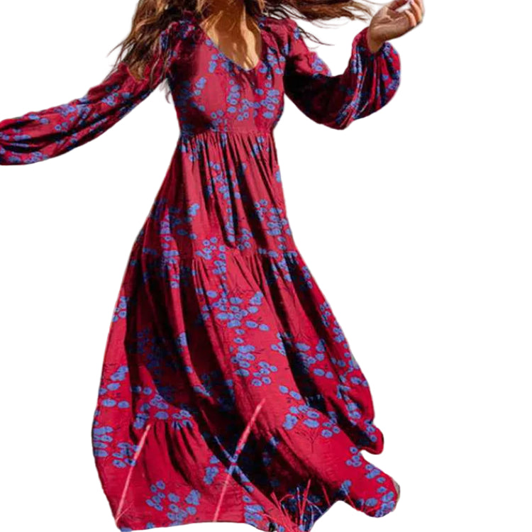 Woman in a red floral dress standing in a field with trees and sky in the background